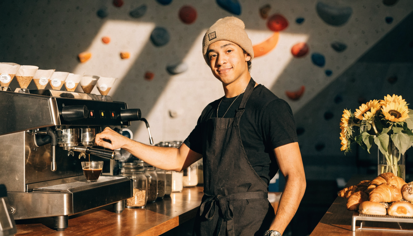 A barista pulling an espresso shot beside the climbing gym floor