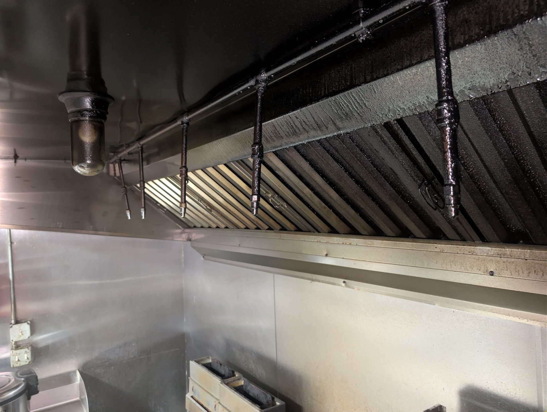 Commercial kitchen hood baffle filters caked in heavy grease under a hard work light