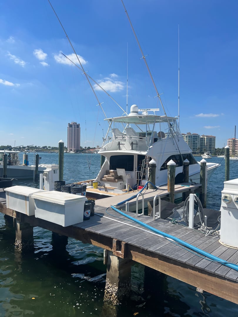 Sportfishing boat docked at a marina with blue cleaning hoses running along the wooden dock