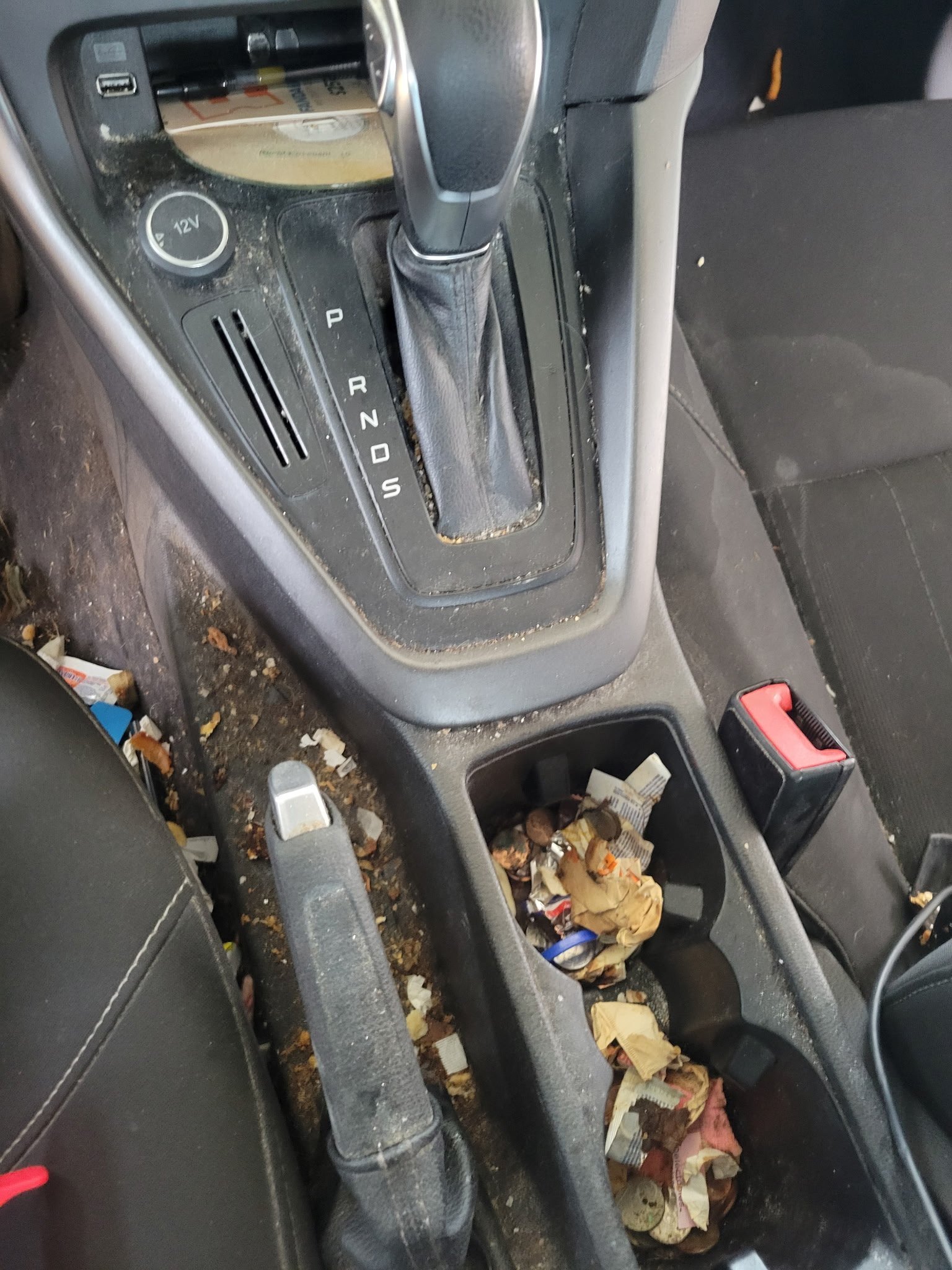 Before: dirty Ford center console with trash-filled cup holders and debris around the shifter