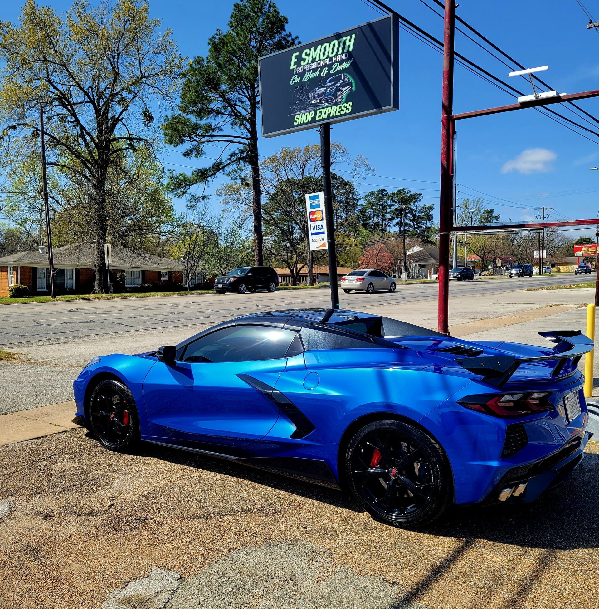 Blue Corvette gleaming beneath the E Smooth Shop Express sign after a hand wash
