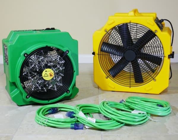 Green bed bug heater and yellow GreenTech fan with coiled green extension cords on a tile floor, ready for setup