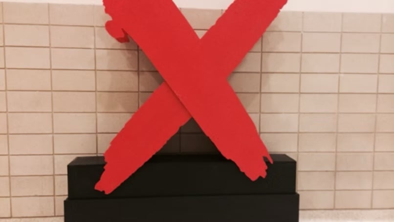 A large red X sculpture on a black pedestal, an End It Movement awareness display against a tiled wall